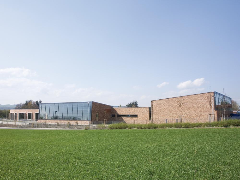 Die horizontal ausgerichteten Erweiterungsbauten der Rheinischen Förderschule Euskirchen integrieren sich harmonisch in die Umgebung. Akzente setzen die darüber hinausragenden Baukörper der Turn- und der Schwimmhalle.