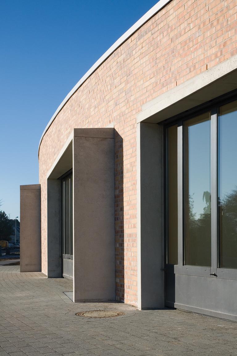 Die sägezahnartigen Fensterrahmen aus Betonfertigteilen verleihen dem bogenförmigen Baukörper mit den Klassenräumem Rhythmik und Plastizität. Sie fungieren zudem als Sonnen- und Witterungsschutz.