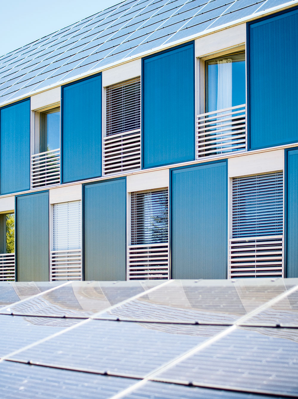 Südwestfassade mit Solarkollektoren und dachintegrierter Photovoltaik. Im Vordergrund das Dach des Nebengebäudes.
