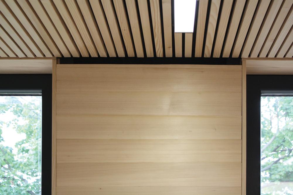 Holz ist auch bestimmendes Material im Innenraum. Die horizontale Wandverschalung und die Deckenuntersicht aus Weißtanne strukturieren den Raum. Im Deckenbereich ist der Lüftungsauslass gut zu erkennen.
