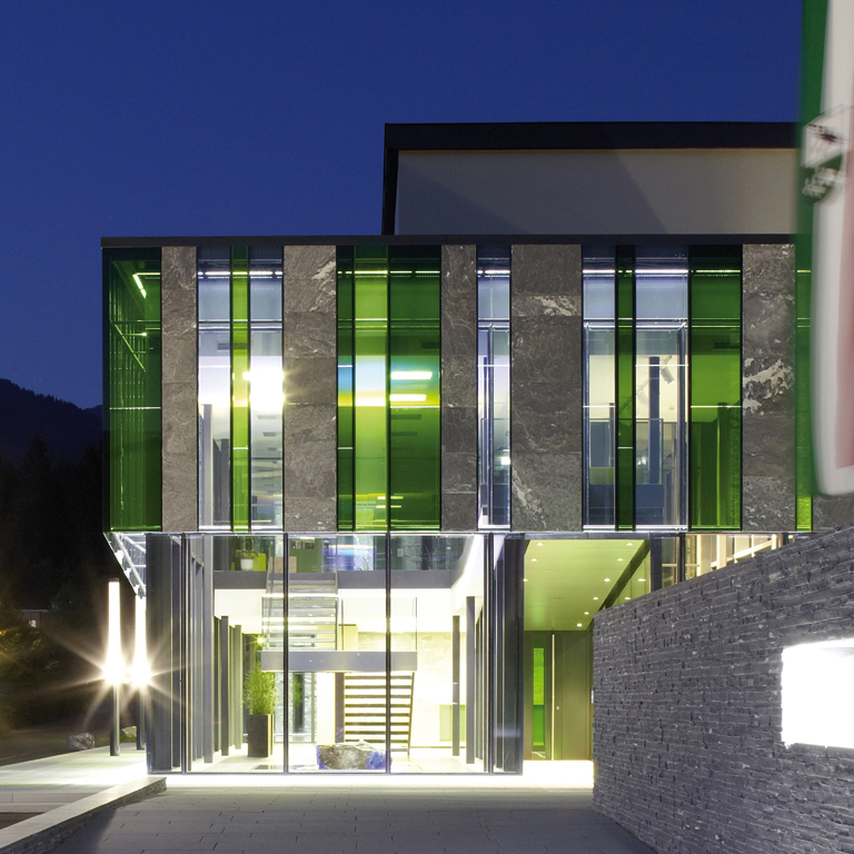 Natursteinlisenen in unterschiedlichen Breiten und Verbundsicherheitsgläser in verschiedenen Grüntönen charakterisieren die Fassade des Foyerbaukörpers und schaffen regionalen Bezug.