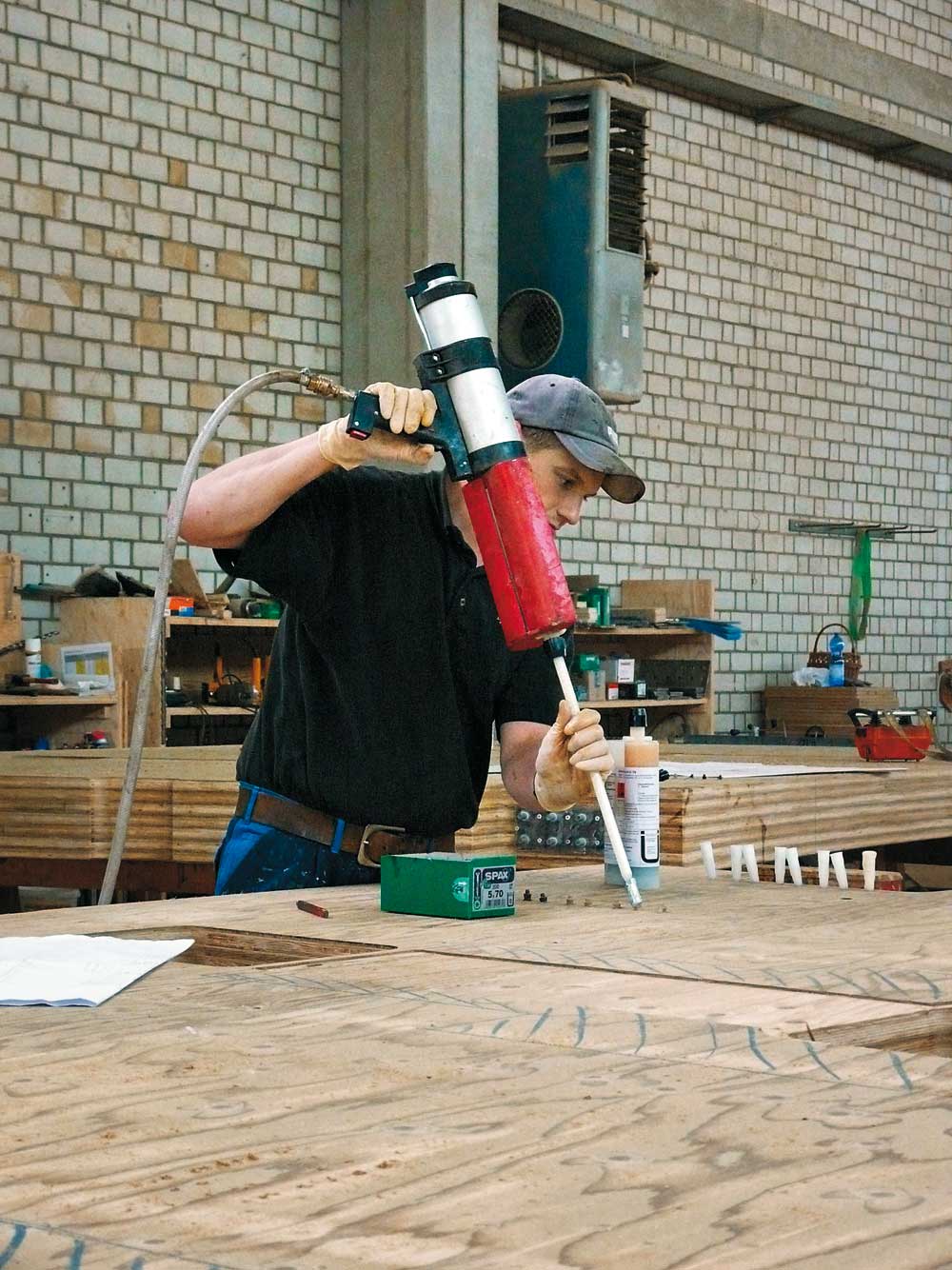 Über Nippel wird der Kleber am hinteren Ende in den Hohlraum der Bohrung um die eingelegten Gewindestangen gepresst, bis er am vorderen Ende in weißen Kontrollröhrchen austritt.