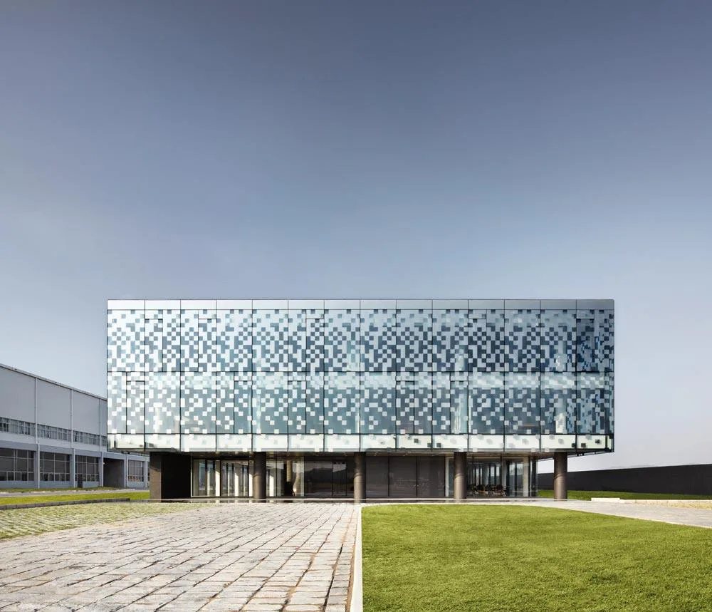 Das neue, insgesamt 8 000 m² umfassende Gebäudeensemble befindet sich in direkter Nachbarschaft zu der Fabrikation von Taiwan Glass in Fujian. Neben dem dreistöckigen Bürobau mit der markanten Glasfassade gibt es noch ein sogenanntes Gatehouse und ein Technikgebäude mit einer eher monolithischen Erscheinung.