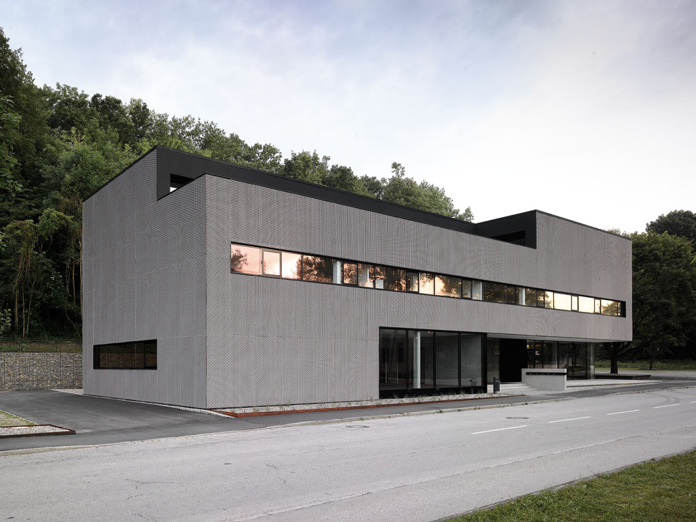 Der gesamte Baukörper wirkt wie ein präzises, überdimensionales Werkstück aus Aluminium und schafft damit den Bezug zur Historie des Orts. Denn Töging war bis in die 1990er Jahre hinein durch die Produktion der Vereinigten Aluminium Werke industriell geprägt.