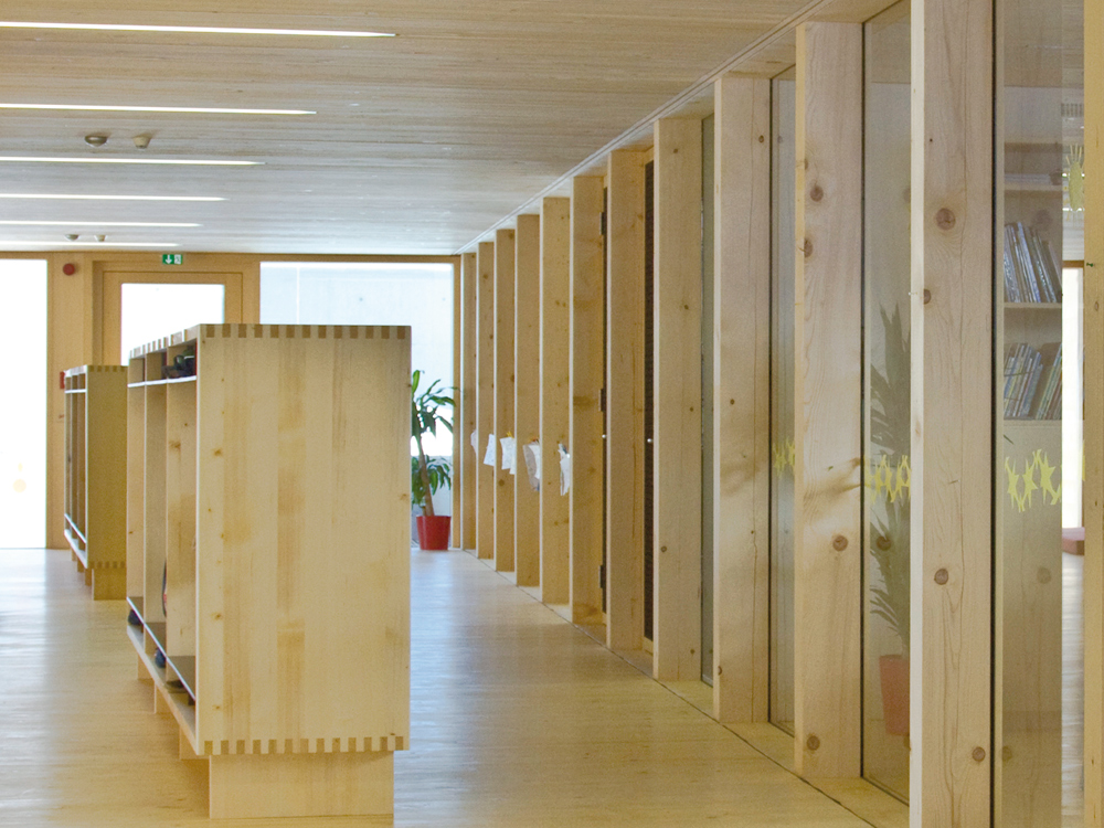 Holz ist auch im Inneren das dominierende Material. Neben den Böden, Wänden und Decken sind auch die meisten Möbel aus der heimischen Fichte gefertigt. Lehmwände im Bereich der Garderoben helfen, das Raumklima auf natürliche Weise zu re gulieren. Filzplatten an Türen, Wänden und Möbeln verbessern die Raumakustik.