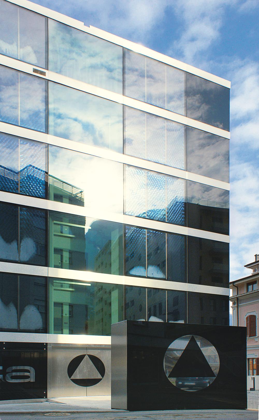 Wohngebäude in Lugano (CH); DeAngelis Mazza Architetti: fassadenintegrierte, geschosshohe Flachkollektoren zur Warmwassererzeugung. Zusätzliche PV-Module auf dem Dach decken den Strombedarf des Gebäudes.