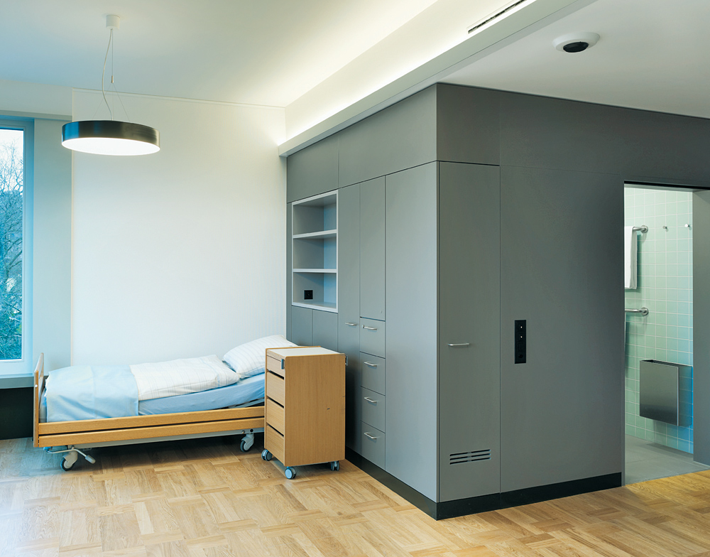 In den Zimmern nimmt ein grau beschichteter Block Bad, Lüftungstechnik, indirekte Beleuchtung, Schubladen, Regale und Elektroinstallation auf.