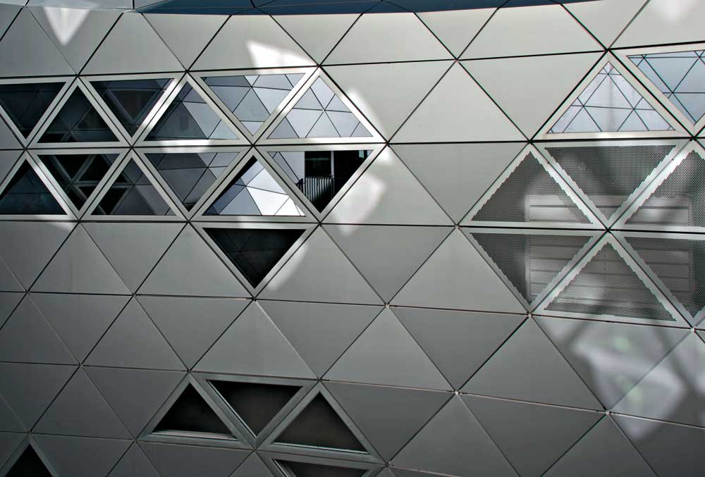 homogene Gebäudehülle aus opaken Aluminium- Verbundplatten, Lochblechen und Glasfeldern