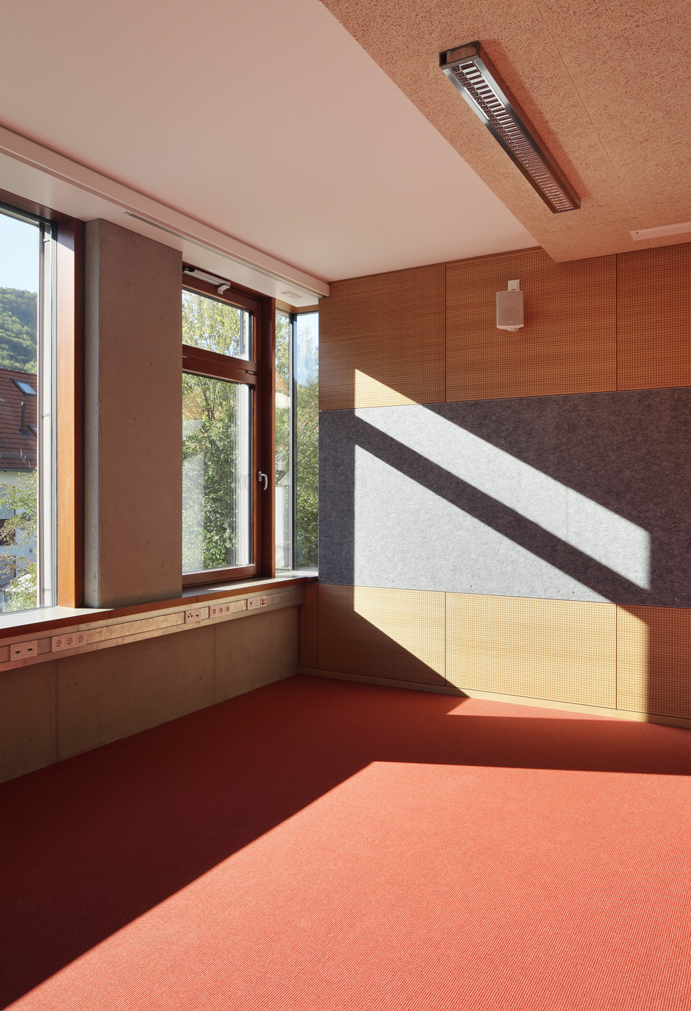 Klassenzimmer an der Gebäudeecke. Die Fenster lassen sich manuell öffnen; darüber gelegene Kippflügel unterstützen die Nachtlüftung.