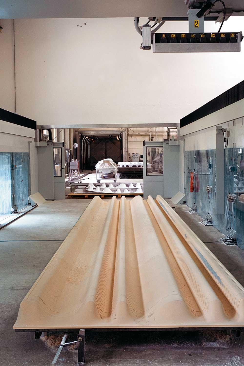 Tiefziehen der Acrylglaspaneele. Die ebenen Acrylglasplatten werden auf die CNC-gefräste Form gelegt, im computergesteuerten Ofen (hinten im Bild) bei 160 °C zum Schmelzen gebracht und durch Vakuum in die Form gesaugt. Nach langsamem Abkühlen wird das Paneel auf 80 °C erwärmt, um die Materialspannung zu relaxieren.