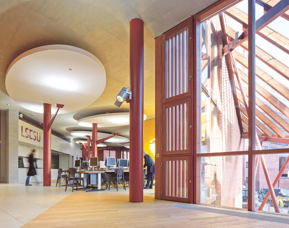 Blick ins Café im 1. Obergeschoss mit den Akustik-Deckensegeln; rechts das Glasvordach über dem Eingangsbereich