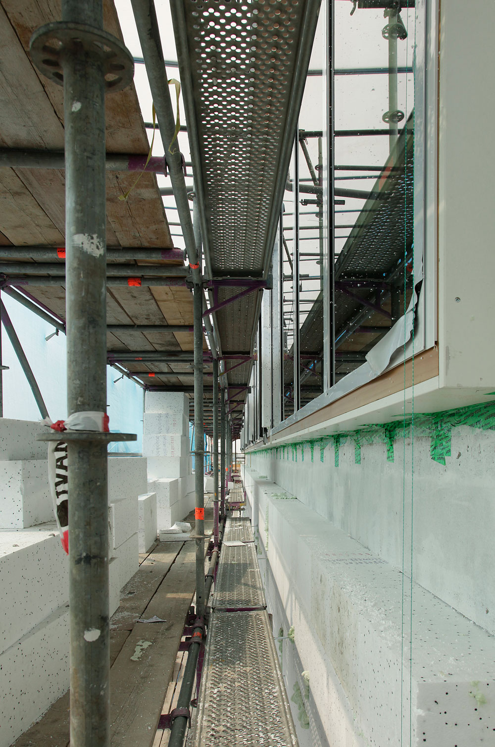 Fassade während des Umbaus. Auskragende Laibungen aus Multiplexplatten erlauben es, die Fenster in der Dämmebene anzubringen.