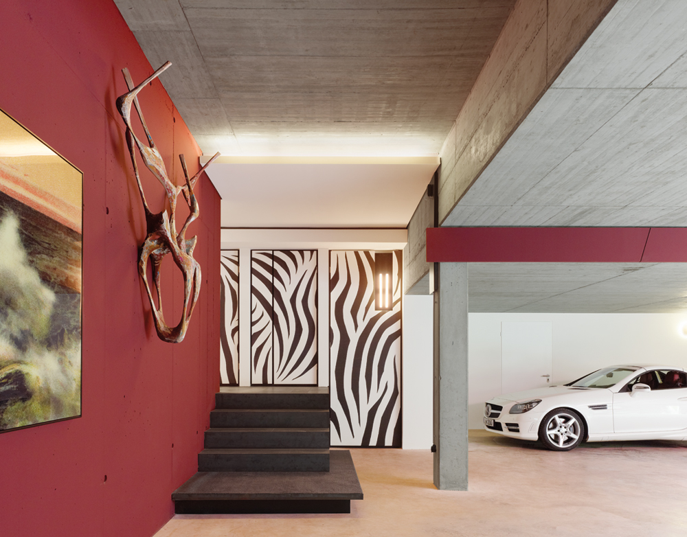 Da die Bewohner ihr Haus oft über die Garage betreten, schenkte der Architekt dieser Situation seine besondere Aufmerksamkeit. Eine farbenfrohe Wandgestaltung und ausgewählte Kunstwerke begleiten den Ankommenden.