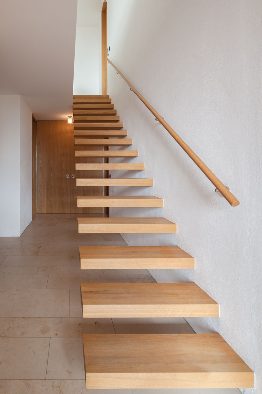 Als Kontrast zu den eher kühl wirkenden Sichtbetonflächen wählte der Architekt warmes Eichenholz für die Ausbildung der Fenster, Türen und Ausbauelemente wie Treppe und Einbaumöbel.