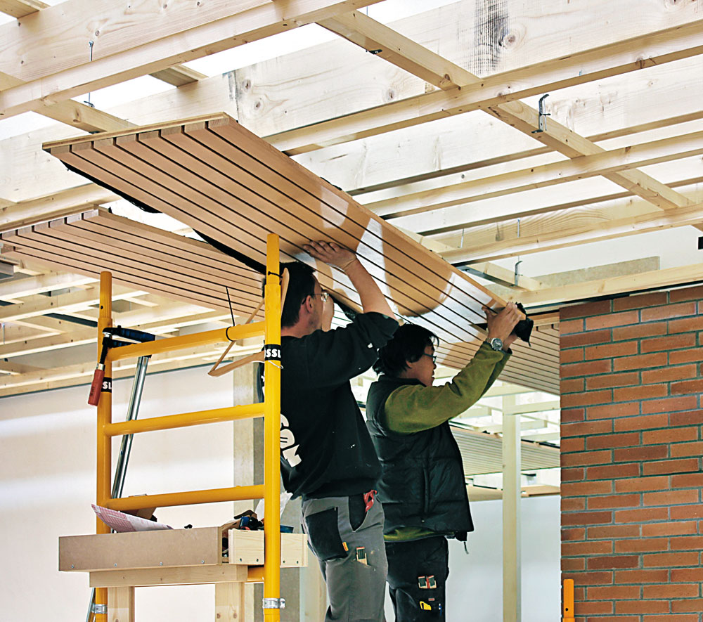 Montage der Deckenpaneele aus kanadischer Hemlocktanne im Originalformat. Die temporäre Holzbalkenkonstruktion spannt von Wand zu Wand.