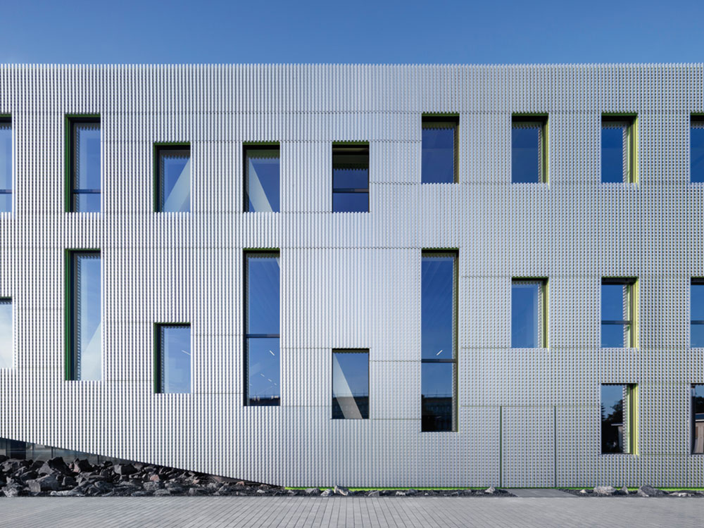 Durch die mehrschichtig aufgebaute Gebäudehülle erfährt die Fassade ein sich je nach Blickwinkel und Lichtverhältnissen änderndes Erscheinungsbild.