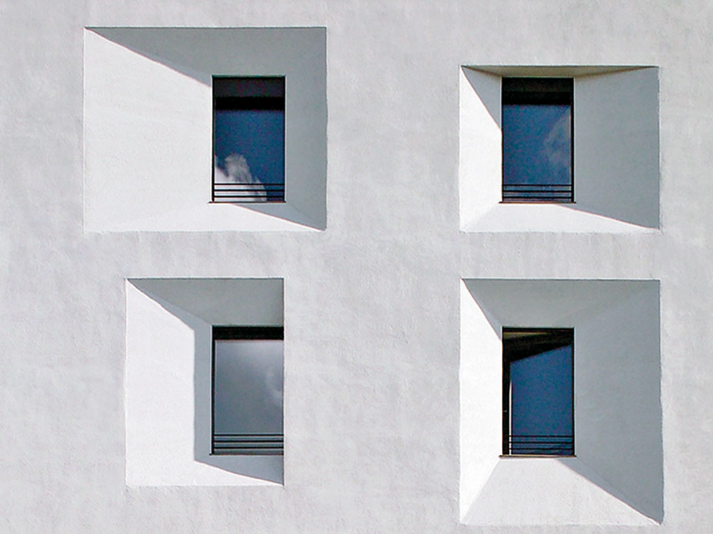 Sanierung eines Bürogebäudes in Bozen, Michael Tribus 2005: Mit der ersten Passivhaussanierung eines Bürobaus etablierte sich das − seither vielfach kopierte − Motiv der abgeschrägten Fensterlaibungen, die hohen Tageslichteinfall auch bei dicken Dämmschichten ermöglichen.