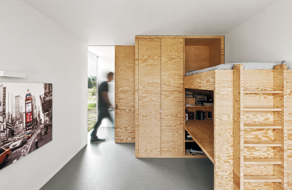 Für »Home 09« verwendeten i29 Seekieferplatten, die mit ihrer fladerigen Oberfläche den Innenräumen ein wiederkehrendes Motiv verleihen. Es handelt sich dabei um verhältnismäßig günstige Mehrschichtplatten, die auch für Schalungen oder Bautischlerarbeiten genutzt werden. Gestalterisch konsequent werden die Möbel auf Gehrung gefügt oder die Kanten beschichtet, um das Oberflächenbild fortzuführen.