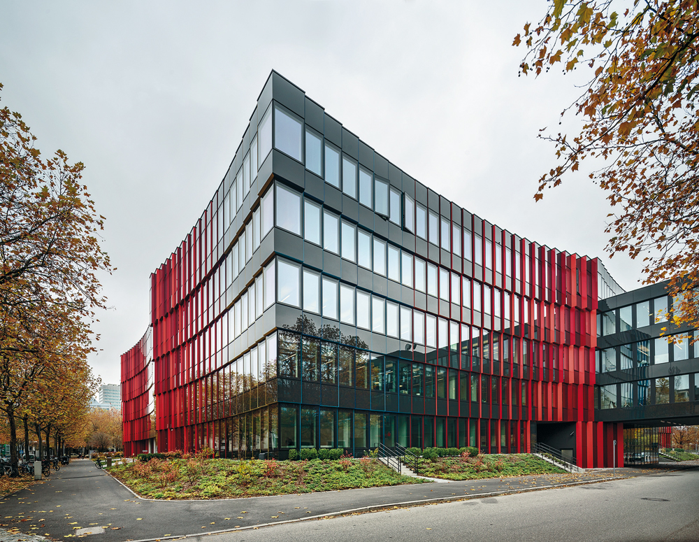 Durch die mit farbigen Aluminiumblechen akzentuierten Versatzsprünge an den Fenstern erscheint das Gebäude bei Betrachtung über Eck jeweils in einer von vier Farbgruppen entweder grün, rot, gelb oder blau.