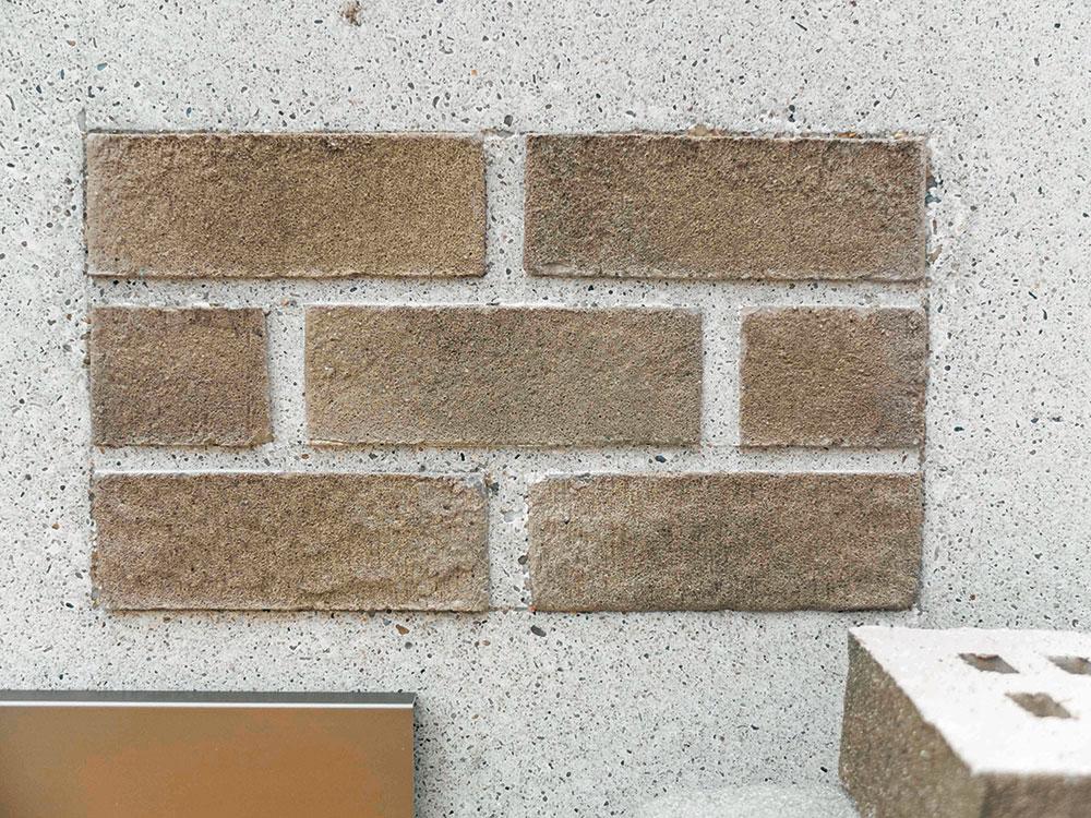 Zunächst wurden mehrere Handmuster angefertigt, bei denen die Riemchen in die Betonoberfläche
eingelegt sind. Anschließend wurde eine Musterfassade im Maßstab 1:1 gebaut, um die Gesamtwirkung zu überprüfen und mögliche Probleme zu erkennen.