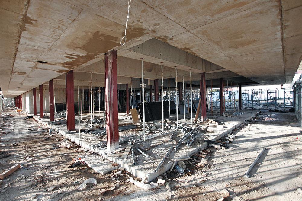 Das Obergeschoss des Querriegels ist auf Stahlstützen aufgeständert und kragt weit über die Fassade aus, um sich vom massiven Bestandsbau abzusetzen. Die unterschiedlichen Betonierabschnitte sind dem fertigen Gebäude nicht mehr anzusehen.