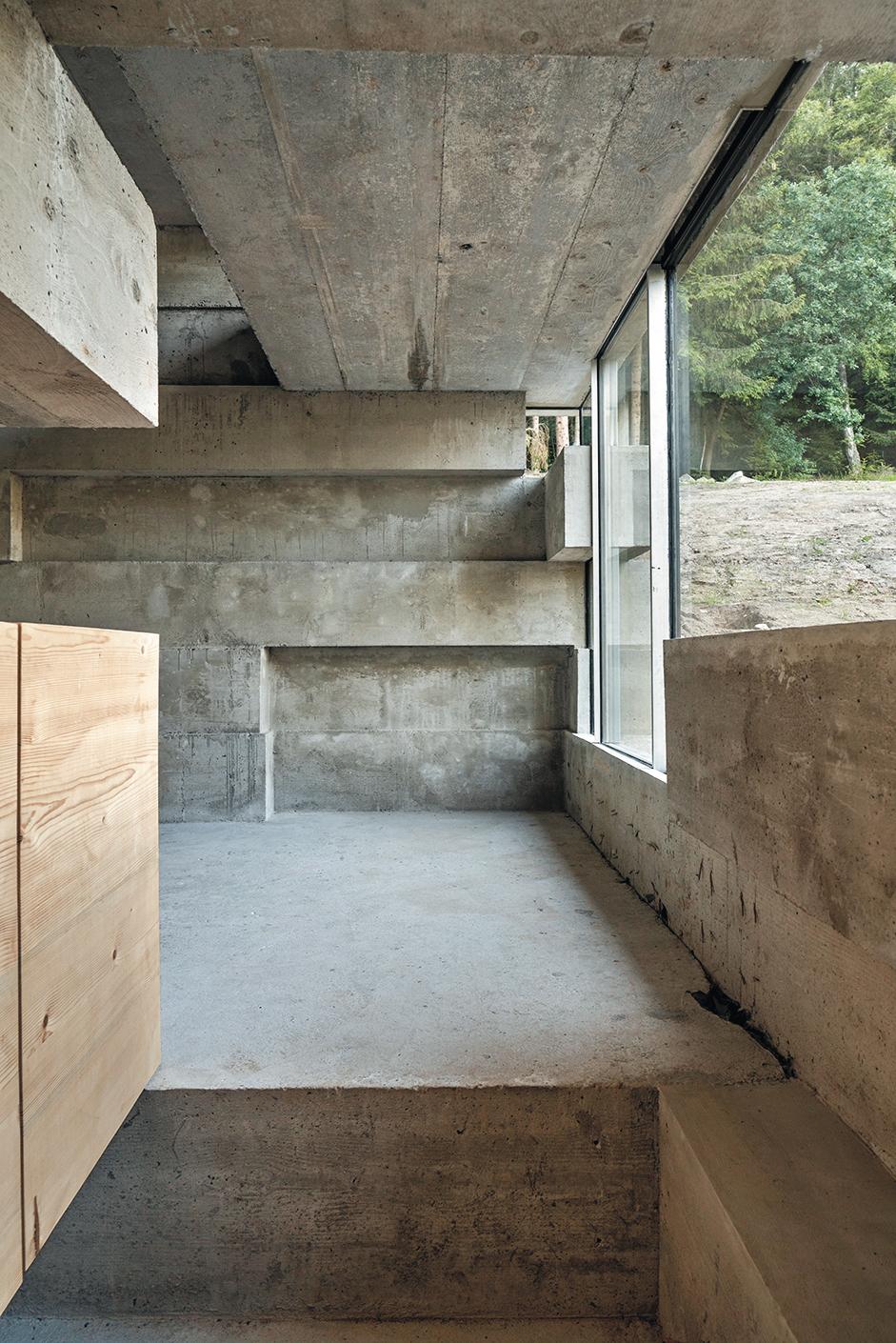 Seit der Sanierung ergänzt Sichtbeton die dunklen Holzbalken und das traditionelle Bruchsteinmauerwerk des historischen Bauernhauses. Aus den Fenstern fällt der Blick auf die Weide und den Wald am Schedlberg.