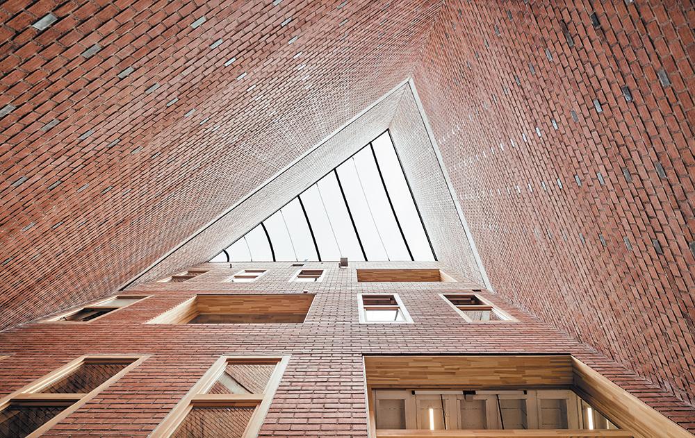 Das dreieckige gebäudehohe Atrium an der Südostecke dient als repräsentative Eingangshalle und zur natürlichen Belüftung bzw. Heizung.