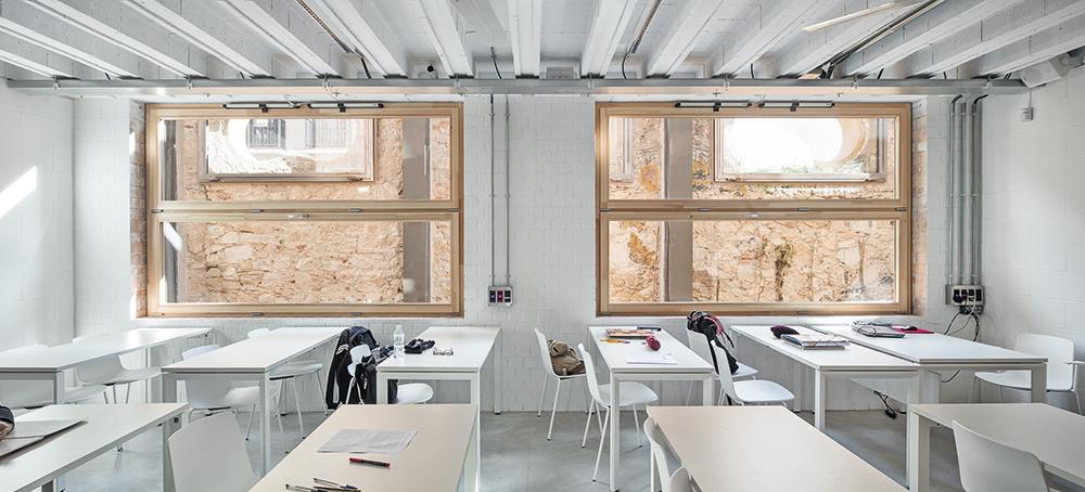 Der Blick aus den Klassenzimmern der unteren drei Geschosse ins Atrium der Südostfassade wirkt wie der Blick in eine Baustelle. Im 4. OG, das die alte Fassade überragt, übernimmt ein Screen aus Glasbausteinen die Funktion des Blendschutzes.