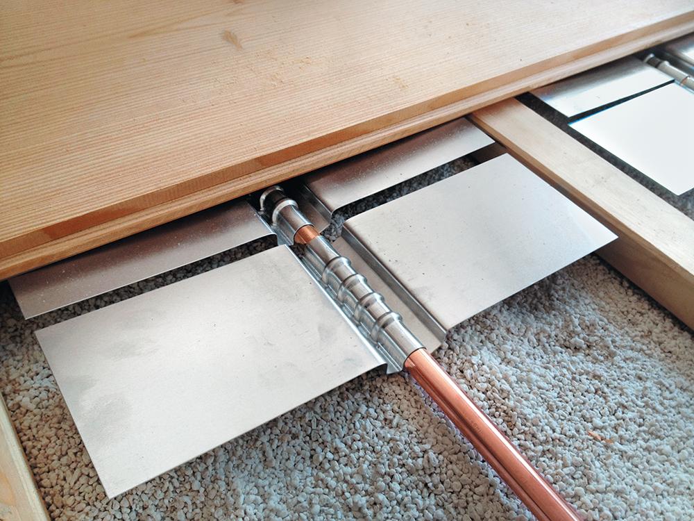 Auf das Wesentliche reduziert: Fußbodenheizungssystem im Trockenaufbau aus Kupferrohren und aufgesteckten Aluminium-Wärmeleitblechen.