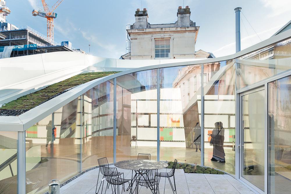 Die geschützte Dachterrasse wird von gebogenen Gläsern eingefasst.