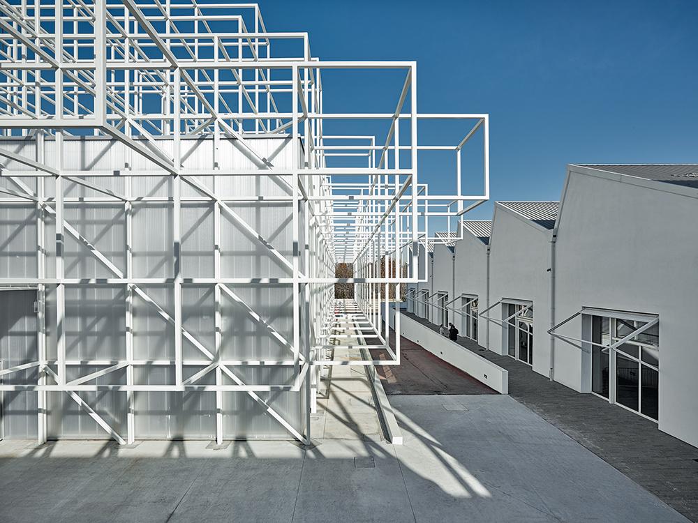 The white steel frame distinguishes the new building from the sober shed halls of the former foundry. Stairs between the steel struts lead up to the building’s roof.
