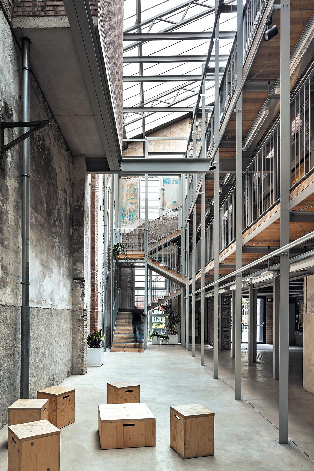 Mit minimalen Mitteln bauten Harquitectes die ehemalige Arbeiterkooperative Lleialtat Santsenca in Barcelona zum Bürgerzentrum um. Eine überdachte Erschließungszone mit Stahlskelett verbindet die drei Bestandsbauten zu einem Ganzen.