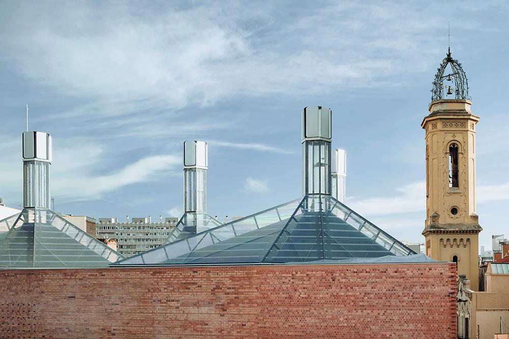 Hightech-Ästhetik hinter Altbaufassaden: Die Foliendächer am Bürgerzentrum Cristaleries Planell in Barcelona dienen als Solarkamine, die die natürliche Entlüftung unterstützen.