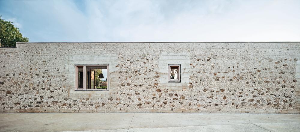 In der Fassade dieses Hauses in Ullastret verwendeten die Architekten die Steine aus der abgebrochenen Grundstücksmauer wieder. Der Beton wurde abgespitzt, um den Steinzuschlag freizulegen.