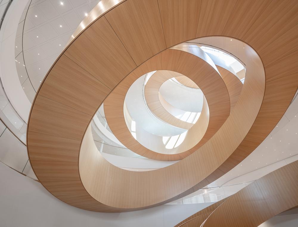 Ringförmige Treppen verbinden die fünf Geschosse. Beim Blick ins Atrium ergibt sich eine optische Durchdringung analog zu den olympischen Ringen.