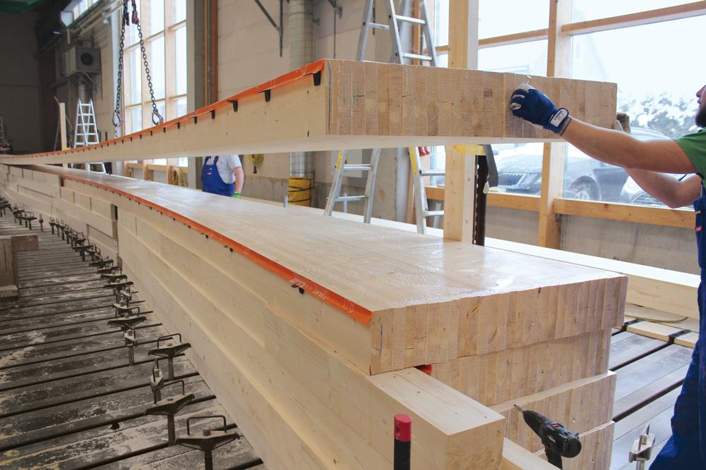 Fertigung des Brückenträgers: 13 je 20 cm breite Brettschichtholzsegmente werden liegend blockverleimt.