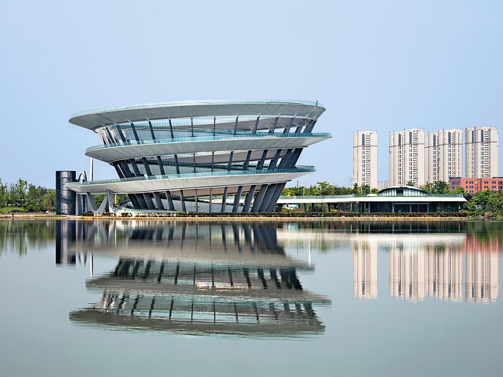 Die Meixi Urban Helix in Changsha von KSP Jürgen Engel Architekten bildet den Endpunkt einer aufgeständerten Promenade aus der Stadt zu einem künstlichen See. Der Weg führt außen am Stützenkranz empor und auf der Innenseite wieder hinunter.