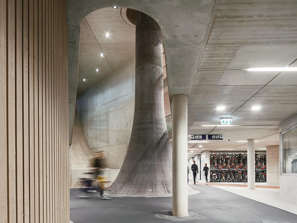 Ein Gebäude, zwei Welten: Über den Bahnhofsvorplatz breitet sich in 25 m Höhe ein Stahl- und Membrandach. Seine Stützen verbreitern sich unter der Erde zu einer charakteristischen Trompetenform.