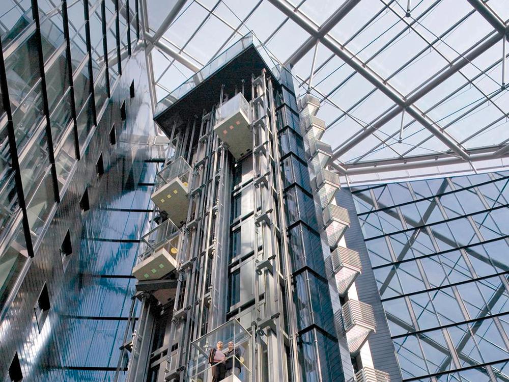 Mehrkabinensystem mit zwei unabhängigen Aufzügen pro Schacht. Das Diagramm rechts zeigt eine Anwendung der Technologie in einem 60-geschossigen Gebäude, wobei eine Aufzugsgruppe die untere und die andere die obere Gebäudehälfte erschließt.