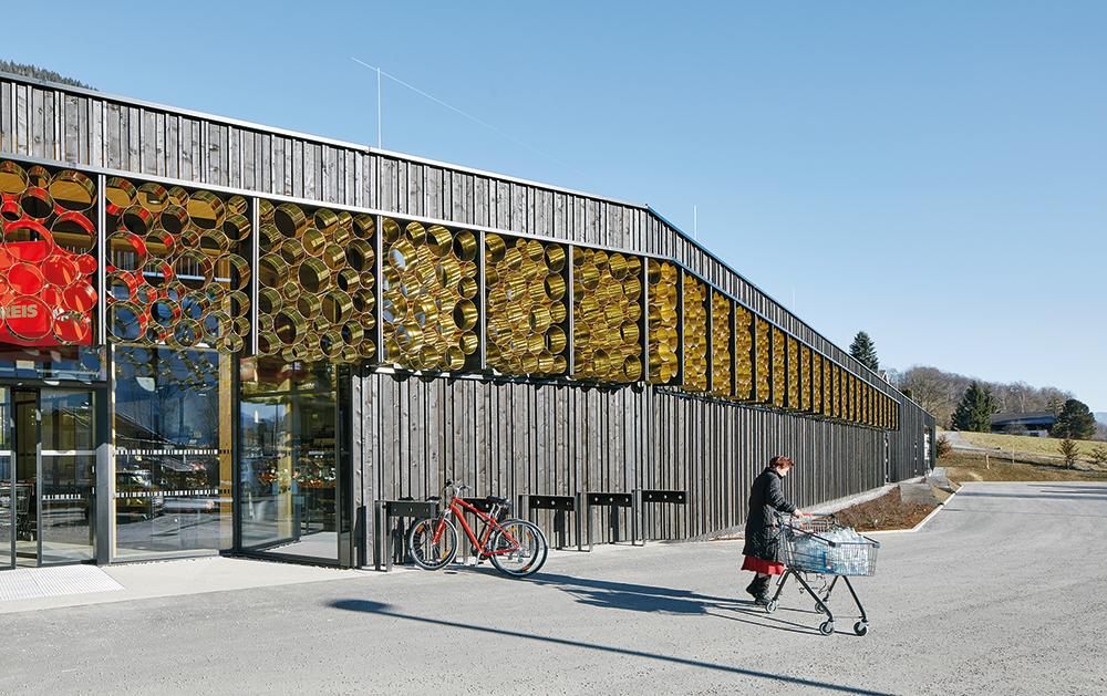 Beim Supermarkt in Piesendorf von Fügenschuh Hrdlovics Architekten sind vorgehängte Messing-zylinder Blickfang und Brise Soleil in einem.