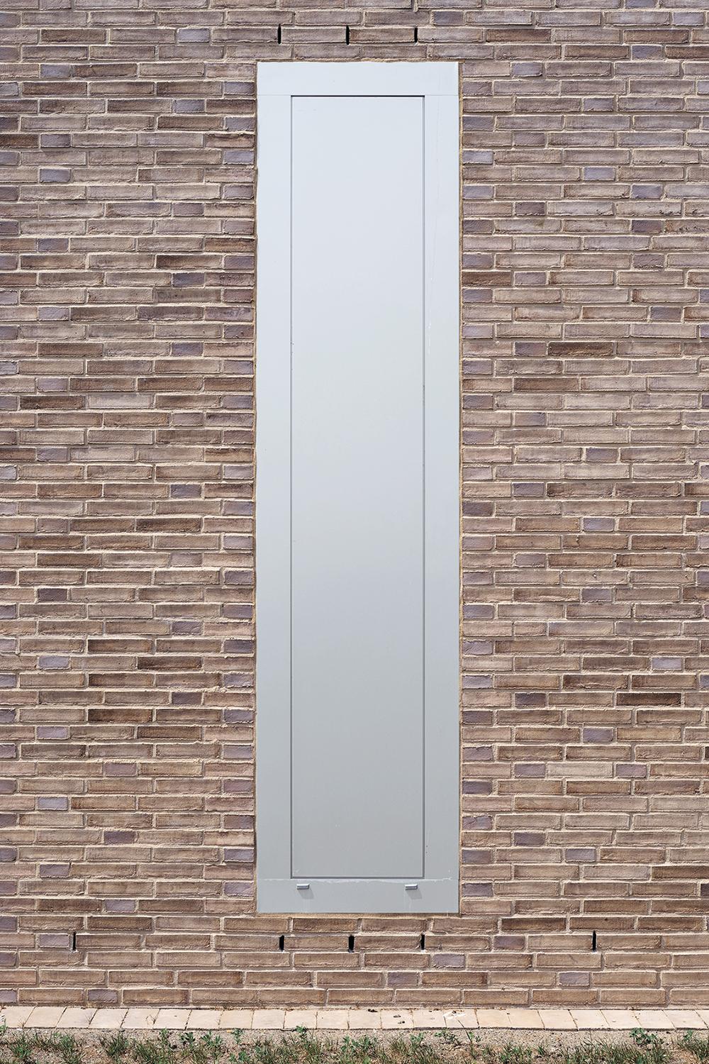 The tall, narrow metal smoke-extraction openings recall windows. They break down the scale of the building and divide the facade into zones.