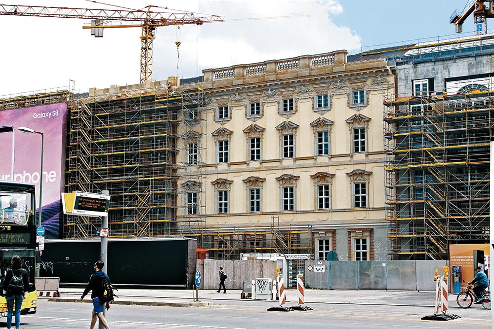 Die wenigen erhaltenen Originalsteine, die Kriegszerstörung und Abtransport überstanden haben, sind als Fragmente in die rekonstruierte Fassade integriert und heben sich durch die dunkle Steinfarbe ab.