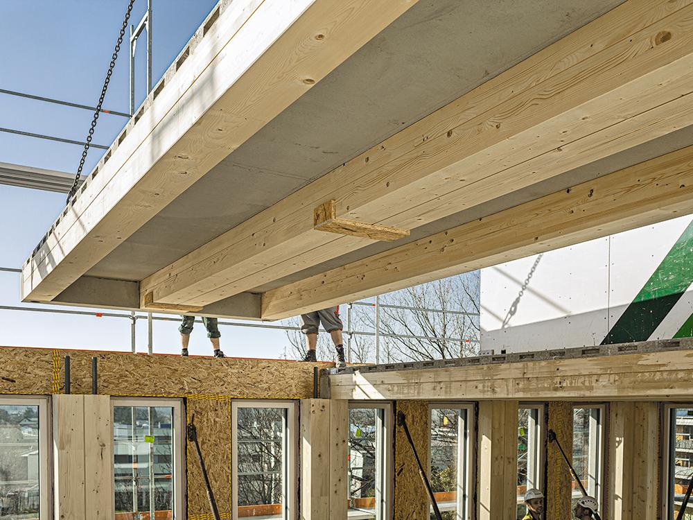 Life Cycle Tower One, Dornbirn: Vier tragende Holzstützen sind bereits vor der Montage in ein Außenwandelement integriert. Die Stirnseite der Verbunddeckenelemente ist als integrierter Betonsturz ausgebildet.