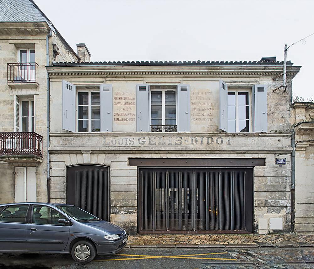 Äußerlich zeugen nur die Metallgitter am Eingang von der neuen Nutzung des Hauses, das noch die Namen seiner Vorbesitzer an der Fassade trägt.