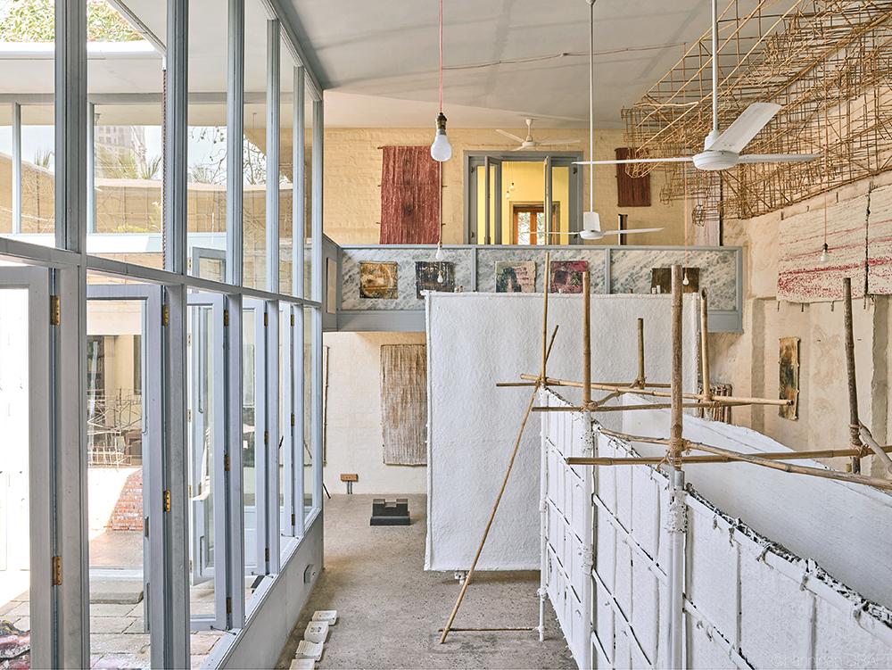 Die doppelgeschossigen Studioräume öffnen sich zu zwei Patios. Dünne Marmorplatten füllen die Rahmenkonstruktion der Fassade.