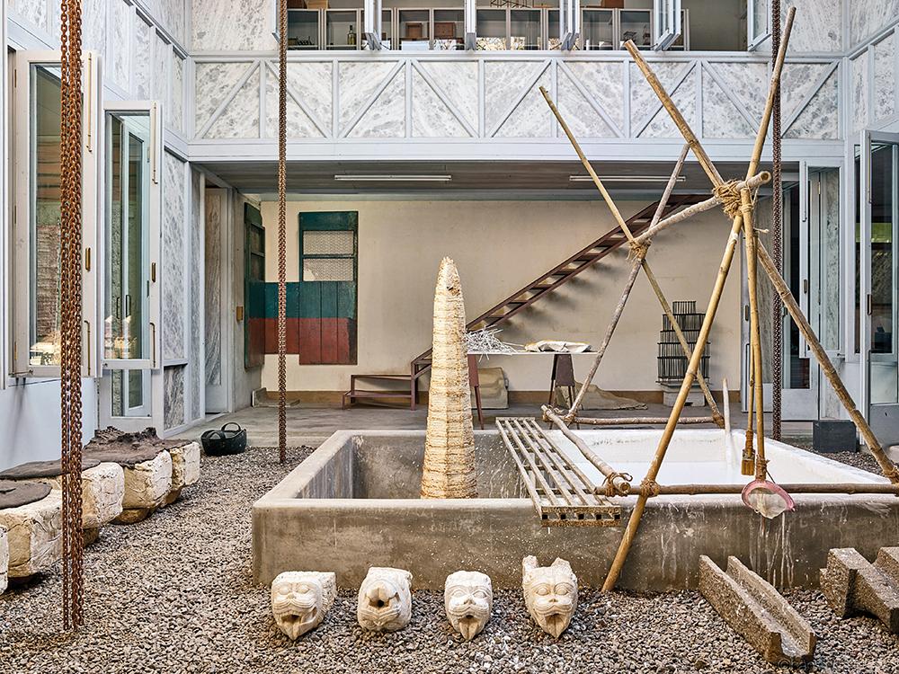 Die doppelgeschossigen Studioräume öffnen sich zu zwei Patios. Dünne Marmorplatten füllen die Rahmenkonstruktion der Fassade.