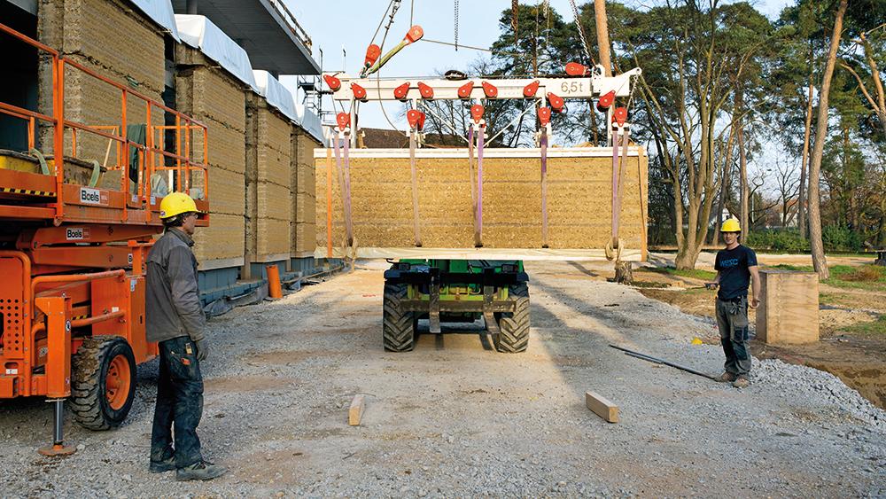 Die Lehmwände wurden inklusive Schaumglasdämmung in rund 30 m langen Streifen gestampft, anschließend in große Blöcke zerschnitten, in einer Halle neben dem Bauplatz zwischengelagert und schließlich am Rohbau montiert.
