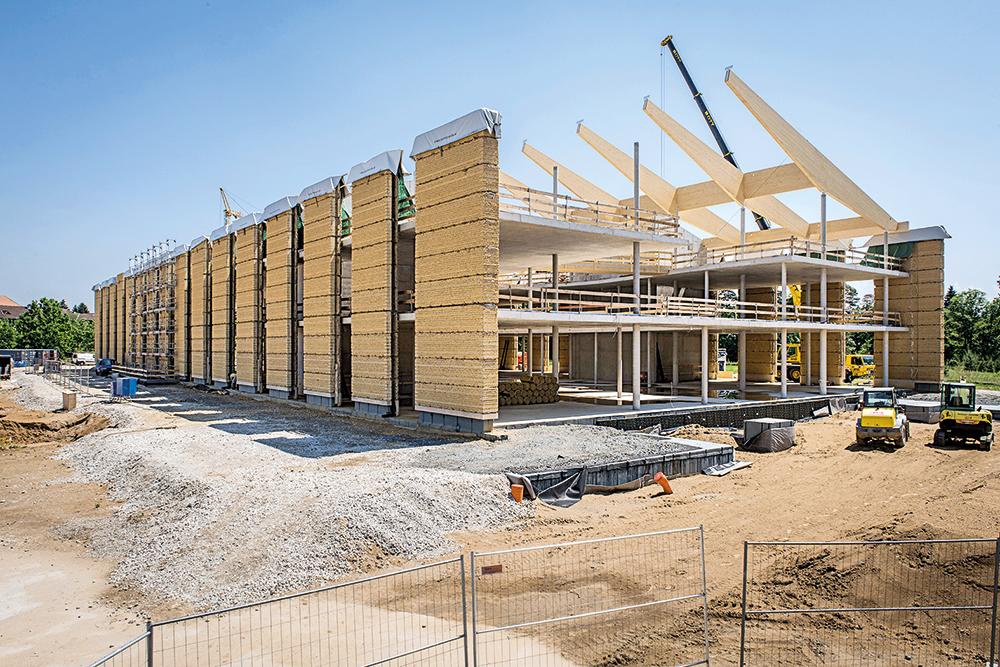 Die Lehmwände wurden inklusive Schaumglasdämmung in rund 30 m langen Streifen gestampft, anschließend in große Blöcke zerschnitten, in einer Halle neben dem Bauplatz zwischengelagert und schließlich am Rohbau montiert.