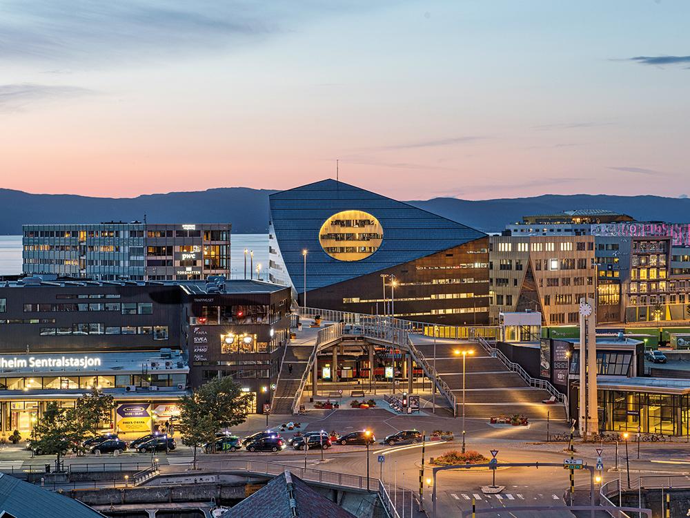 Der Neubau liegt direkt am Hauptbahnhof von Trondheim in einem Konversionsgebiet am Hafen. Eine Fußgängerbrücke verbindet das Quartier mit dem Stadtzentrum.