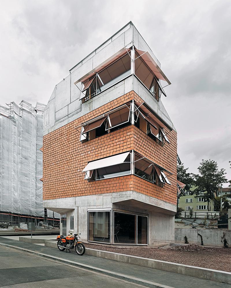 Die Dreiteilung der Fassade, die filigranen Holz-Aluminiumfenster und der textile lachsrosa Sonnenschutz tragen maßgeblich dazu bei, dass das neue Wohnhaus dem Maßstab des Quartiers entspricht.